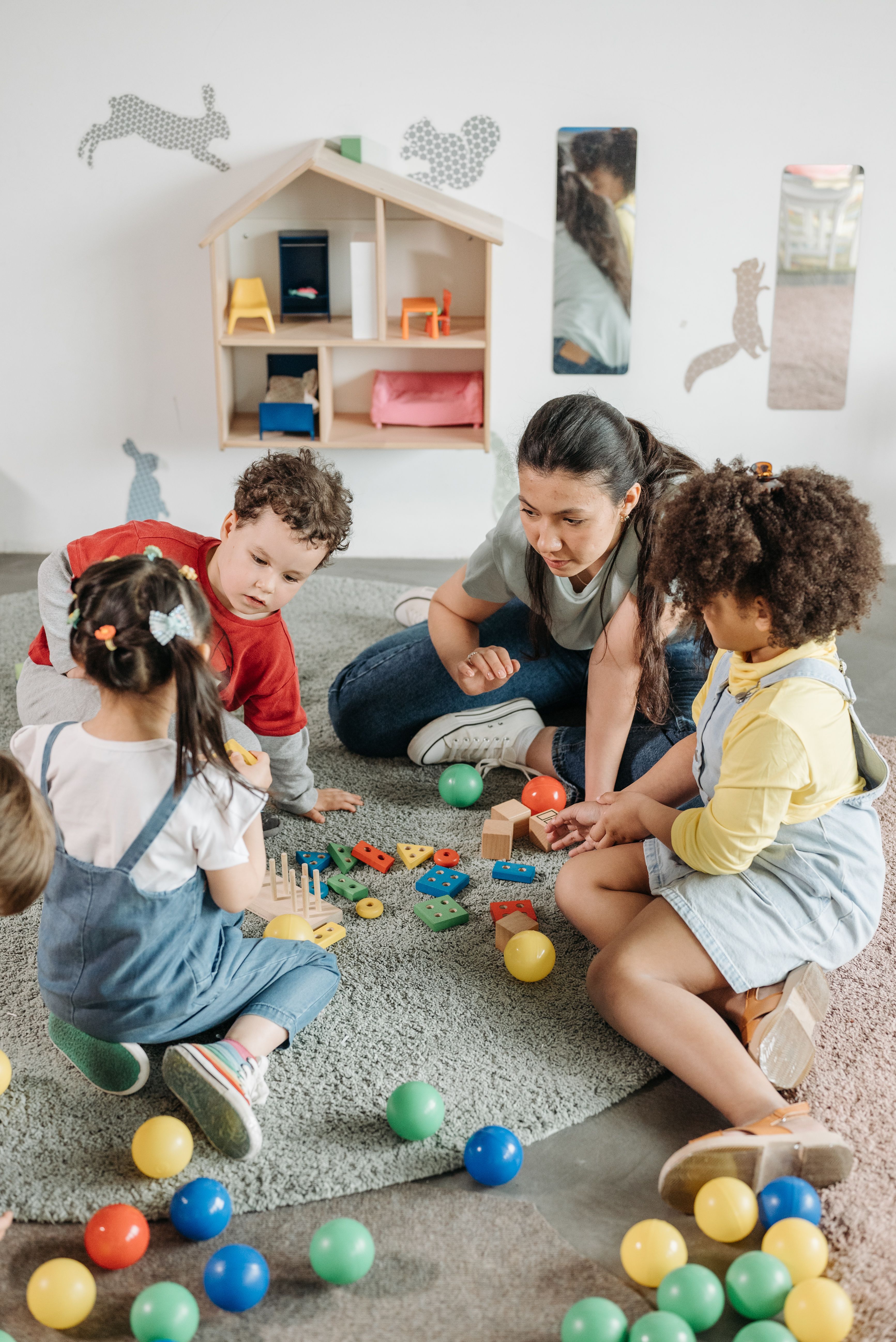 Children playing with colorful toys on a carpet with a teacher